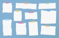 Pieces of ripped white ruled note paper are stuck with colorful sticky tapes on blue background