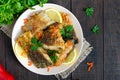 Pieces of roasted carp with lemon and greens on a plate on a dark wooden background. Royalty Free Stock Photo