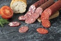 pieces of sausage cut into circles near bread and tomato on a black background. three kind of different sausages on a Royalty Free Stock Photo