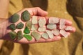 Pieces of sea glass are laid out on an open hand showing colours from green to white