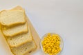 Pieces of sliced fresh corn bread on a wooden Board and a plate of corn grains on the table. White isolated background, top view, Royalty Free Stock Photo