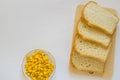 Pieces of sliced fresh corn bread on a wooden Board and a plate of corn grains on the table. White isolated background, top view, Royalty Free Stock Photo