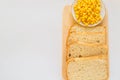 Pieces of sliced fresh corn bread on a wooden Board and a plate of corn grains on the table. White isolated background, top view, Royalty Free Stock Photo