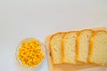 Pieces of sliced fresh corn bread on a wooden Board and a plate of corn grains on the table. White isolated background, top view, Royalty Free Stock Photo