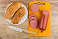 Pieces of smoked sausage on cutting board, bread in plate Royalty Free Stock Photo