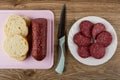 Smoked sausage, slices of bread on cutting board, knife, slices of sausage in plate on wooden table. Top view Royalty Free Stock Photo