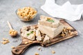 Pieces of sunflower and peanut halva and mint leaves on a cutting board and a bowl of nuts on the table. Caloric oriental dessert Royalty Free Stock Photo