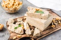 Pieces of sunflower and peanut halva and mint leaves on a cutting board and a bowl of nuts on the table. Caloric oriental dessert Royalty Free Stock Photo