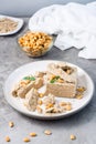 Pieces of sunflower and peanut halva and mint leaves on a plate and a bowl of nuts on the table. Caloric oriental delicacy. Royalty Free Stock Photo