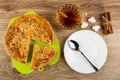 Pieces of lemon pie on cutting board, cup of tea with cinnamon stick, sugar, bunch of cinnamon sticks, spoon on plate on wooden