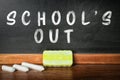 Pieces of chalk and duster on table near blackboard with text SCHOOL`S OUT Royalty Free Stock Photo