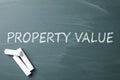 Pieces of white chalk and phrase PROPERTY VALUE on chalkboard, flat lay Royalty Free Stock Photo