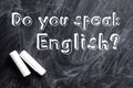 Pieces of white chalk and question DO YOU SPEAK ENGLISH written on blackboard Royalty Free Stock Photo