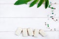 Pieces of white toilet soap , a scattering of colorful pebbles and green fresh leaves on wooden background. Flat layout