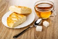 Pieces of wicker pie with cottage cheese in plate, spoon, cup with tea, sugar on wooden table Royalty Free Stock Photo