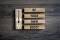 Pieces of wood with pencil rocket and message Be your own boss on wooden background