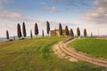 Pienza, Italy - March 17, 2016: House in Tuscany on a hill with cypress trees and a green field in Pienza, Valdorcia