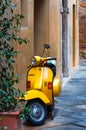 Pienza, Italy - October 13, 2017: Orange Vespa parked on old cozy street in Italy