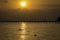 A pier across the sea with silhouettes at sunset