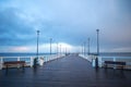 Pier on the Baltic Sea. Many birds on the sea and a wooden pier. There are many lanterns on the pier. A flock of birds over the se