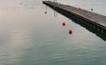 Pier on the harbor with red buoys and reflections in the water at sunset