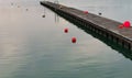 Pier on the harbor with red buoys and reflections in the water at sunset Royalty Free Stock Photo