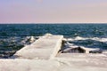 Pier in heavy ice and long icicles on stone in water