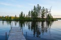 Pier jutting out into reflections of an island in the Chippewa Flowage near the shore of a Northwoods Forest park