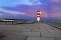 A pier leading to the lake and a red and white lighthouse at Lake Neusiedl in Podersdorf, Austria. In the background is a dramatic Royalty Free Stock Photo
