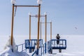 Pier with a lonely man on the frozen sea covered with snow to the horizon. Small figures of people engaged in kite surfing Royalty Free Stock Photo