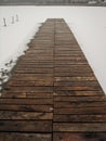 Pier made of wood leading into the frozen lake. Royalty Free Stock Photo