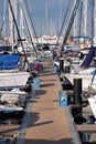 Pier with many parking yachts in calm marina water on bright summer day