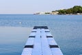 The pier near beach against blue sky in sunny day. Adriatic coast and sea in Slovenia. Holiday and travel concept Royalty Free Stock Photo