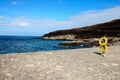 Pier oceanscape with a sandy beach and yellow lifebuoy rings and rocky, forested hills