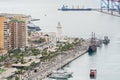 Pier one in the port of Malaga, Spain where is the lighthouse known as `La Farola` and several docked ships, including a galleon,