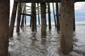 The pier pilings frame the ocean waves as they approach the shore