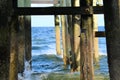 The wood beams of the ocean fishing pier frame the bright ocean sky