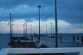 Pier on the sea. The dove sits on the pier. Cloudy cloudy weather. Birds on the sea. Baltic Sea. Many lanterns on the pier.