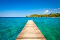 Pier at sea in the summertime. Azure sea and shore with rocks. Clear sea water and clear sky.