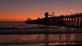 Pier silhouette at sunset, California USA, Oceanside. Surfing resort, ocean tropical beach. Surfer waiting for wave. Royalty Free Stock Photo