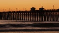 Pier silhouette at sunset, California USA, Oceanside. Surfing resort, ocean tropical beach. Surfer waiting for wave. Royalty Free Stock Photo