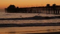 Pier silhouette at sunset, California USA, Oceanside. Surfing resort, ocean tropical beach. Surfer waiting for wave. Royalty Free Stock Photo