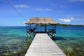 A pier with thatched roof shelter on the beach at Malenge Island, Togian Islands, Sulawesi, Indonesia.
