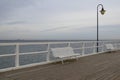 Pier with two white benches and a lantern in the sea in autumn Royalty Free Stock Photo