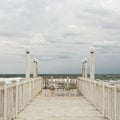 Pier with white wooden handrails at sea during a storm. Royalty Free Stock Photo