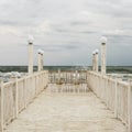 Pier with white wooden handrails at sea during a storm. Royalty Free Stock Photo