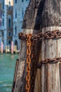 Pier wooden poles tightened together by rusty chains on canal in Venice, Italy Royalty Free Stock Photo