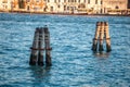 Pier wooden poles tightened together by rusty chains on canal in Venice Royalty Free Stock Photo