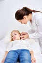 piercing ears to caucasian child girl in medical salon by a doctor using a special device