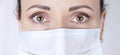 Piercing female look of brown eyes close-up. Portrait of a female doctor in a medical mask